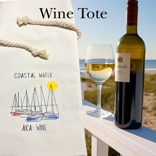 Wine tote with "coastal water, AKA Wine" text near a bottle of wine and a glass on a beach setting