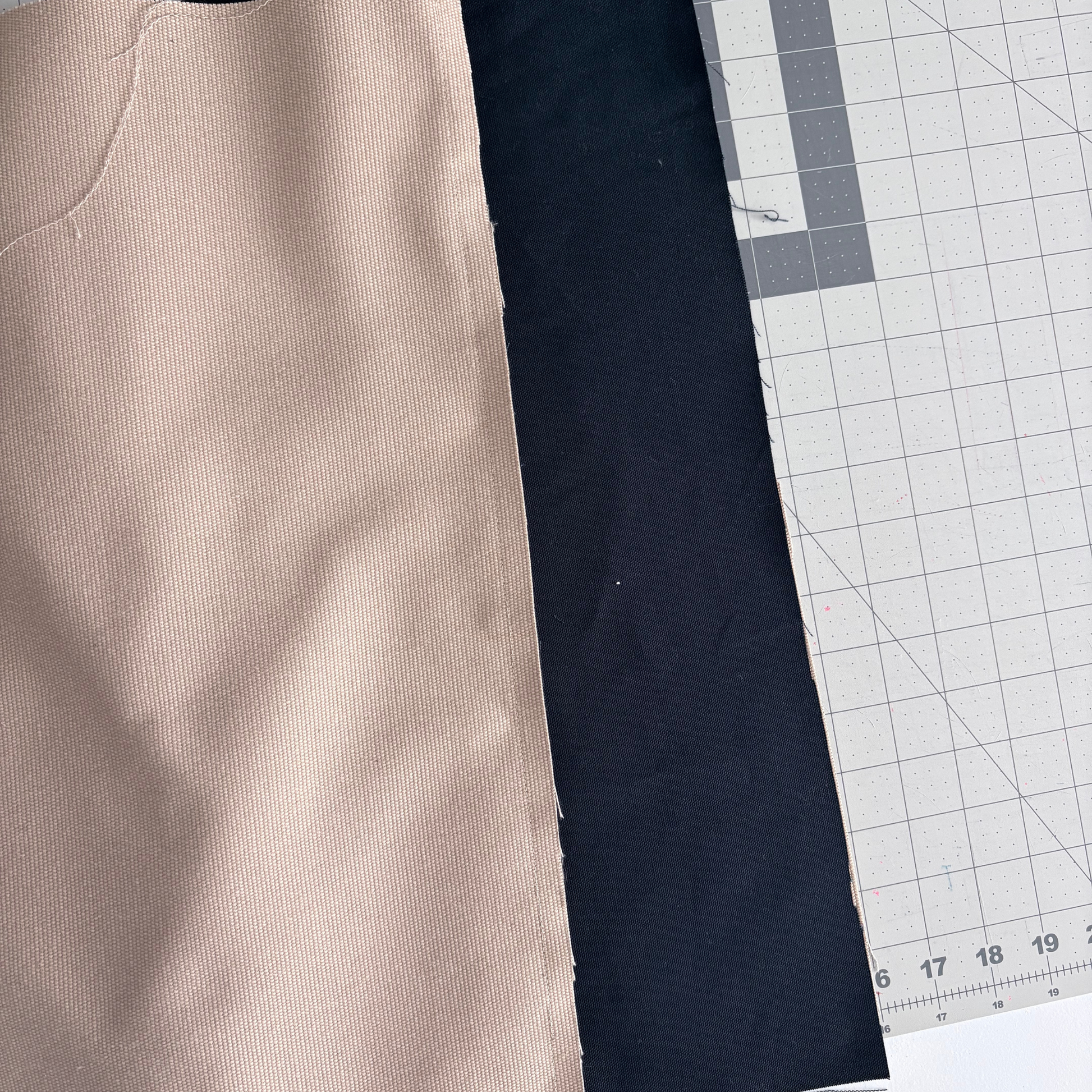 Close-up of fabric swatches on a cutting mat with measurements.