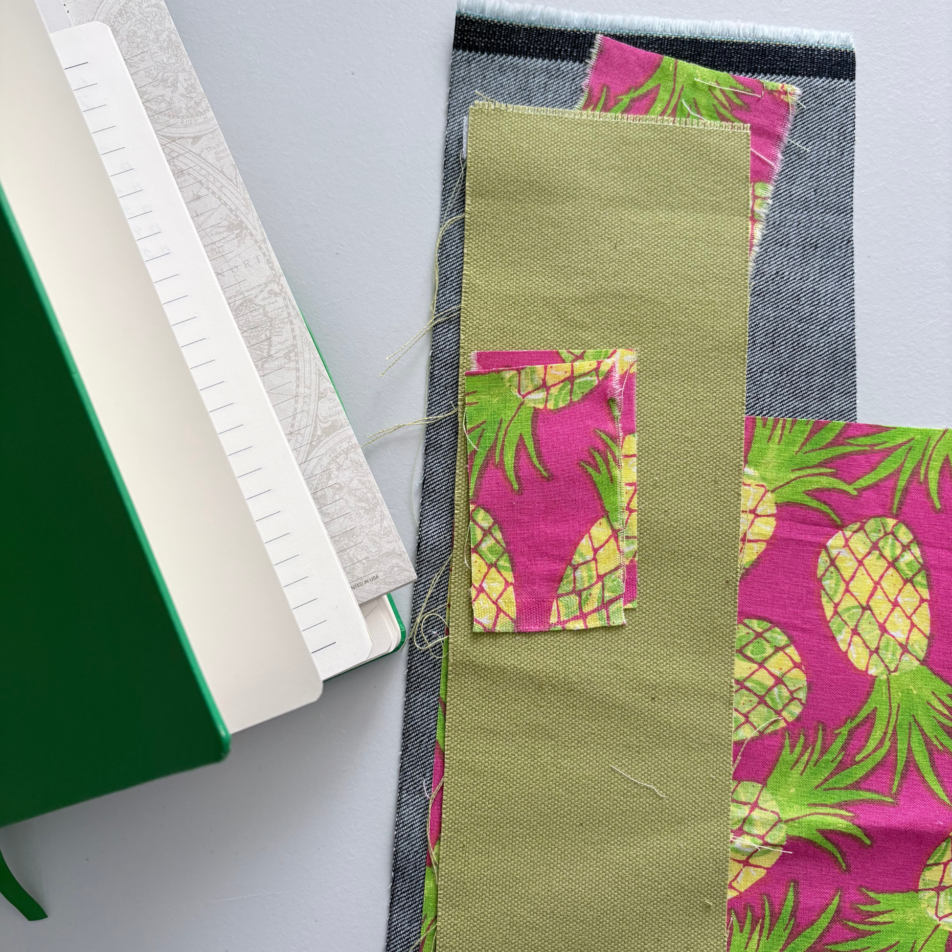 Fabric swatches with pineapple pattern  and notebook on a white background