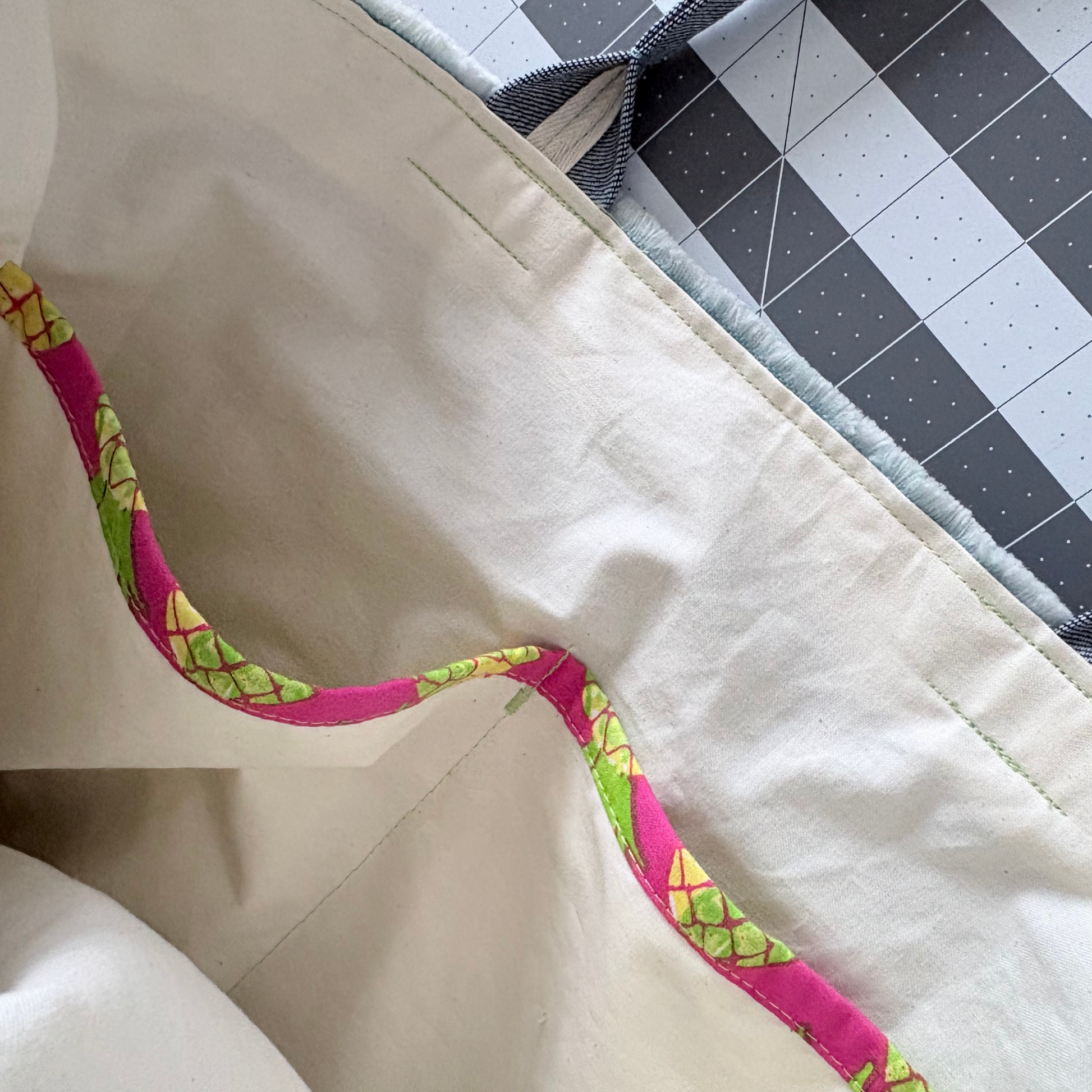 Close-up of a fabric strap with pink and green pattern on a beige background