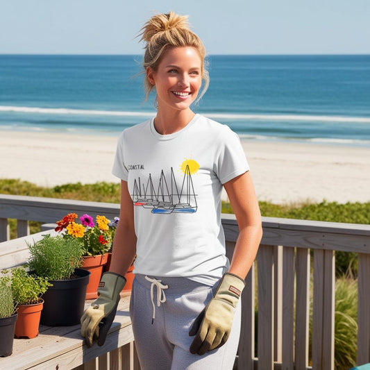 Model wearing a white t-shirt with coastal line art boat design, standing on a deck with a beach and plants in the background.