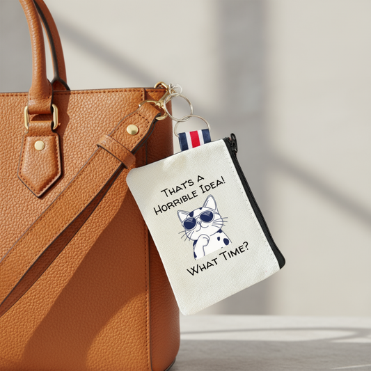 Zip pouch keychain with cat design and humorous text attached to a tan colored handbag.